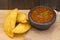 Colombian empanada with spicy sauce on wooden background, typical food of Colombia