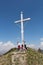 Colombina mountain peak with tourists, cross and blue sky on background
