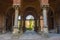 Colonnade portal with a domed ceiling and a cement stone columns with doors on both sides and iron arched gate at the front. Archi