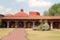 Colonnial farm and country house, stone and red brick construction with arches and green grass garden