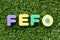 Color alphabet letter in word FEFO abbreviation of first expired first out on green grass background