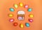 Color Easter eggs laid out in circle and gingerbread Easter cake in center on orange background. Festive Easter layout.