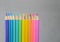 Color pancils with grey background, Group of colorful pencils laying in row striaght line made by pencil tips close up, copy