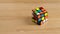 Color puzzle Rubiks cube is rotated and collected in combination on a wooden table. Stop motion animation video. Close