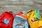 Color rucksacks with school stationery on wooden background