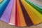 Color stack of test samples for paint or fabric in rainbow spectrum colors on the table.