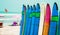 Color surf boards in a stack by ocean