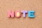 Color toy foam alphabet in word note on cork board