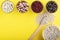 Colored bean in glass jars and wooden spoon of white bean on a yellow background. Image with copy space