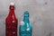 Colored bottles, blue and red glass with a cogged stopper on the neck, on a wooden tabletop
