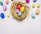 Colored decorative easter eggs with painted faces lie in a nest border ,place for text wooden rustic background top view close