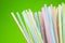 Colored drinking straws on green background
