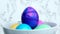Colored Easter eggs in a bowl slowly rotate on light backdrop