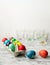 Colored Easter eggs in carton box on kitchen counter, emply glasses wirh remnants of dye