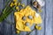 Colored eggs on a bright yellow napkin and meadow yellow tulips. Easter decoration. Rustic kitchen still life