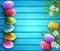 Colored eggs, flowers, daisies, grass lying on a blue wooden board