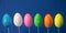 Colored glittering Easter eggs on sticks and blue background.