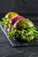 Colored green, yellow and purple burgers on slate board, slate background