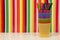 Colored markers, plastic cups stacked and multicolored stripes background
