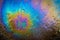 Colored oil stain on the asphalt. A rainbow slick of gasoline. Abstract background