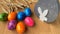 Colored painted eggs rotate on a wooden table against a background of ripe ears of wheat, Easter concept