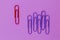 Colored paper red clip outstanding on purple background. minimal