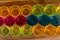 Colored party cups - yellow, orange, pink and blue lined in three rows on a wooden board