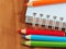 Colored pencils with blank sketch book on wooden background