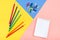 Colored pencils, colored clothespins and a notepad on a tricolor background