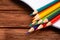 Colored pencils in an open notebook on a dark brown wooden surface. Back to school. Education. Office tool. Empty place for text