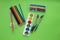 Colored pens,pencils, paints, pens for writing. Colorful items for school, office on a green background