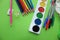 Colored pens,pencils, paints, pens for writing. Colorful items for school, office on a green background