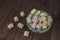 Colored pieces of marshmallow spiral in a plate on a dark wooden table. Sweet rainbow colored candies, marshmallow, aerial dessert