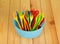 Colored plastic bowl, fork and spoon on background light wood.