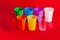 Colored plastic cups on red background