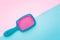 Colored plastic hair brush on bright blue and pink background. View from above. Beauty concept.