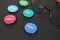 Colored plastic magnetic buttons on a black background next to glasses. Side view. Buttons with words leader, hacker, rebel,