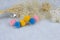 Colored pompon earrings in the shape of three furry balls.Earrings are next to rattan products, flower specimens and other ornamen