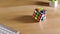 The colored puzzle Rubiks cube is rotated and collected in combination on a wooden table next to a white keyboard. Stop