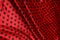 Colored red dotted textile satin fabric folded in folds and waves with highlights and texture