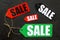 Colored sale labels on black stone background top view