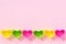 Colored silicone heart shaped molds dish for baking cupcakes lined in row bottom edge on pink paper background. Template for