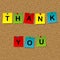 Colored stick notes with words thank you pinned to a cork message board