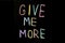 Colored text `give me more`written  on chalkboard