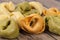 Colored tortellini, ring-shaped pasta on wooden plank