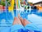 Colored water park slides and pool. Male feet in the water