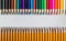 Colored wood pencils in front of simple graphite pencils on table isolated