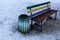 Colored wooden bench and concrete flowerbed outside in the snow