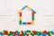 Colored wooden cubes assembled in the shape of a house on a white wooden background. Early development for children. Home, family
