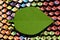 colorful abstract background with different reflection and many beads of different colors on them green paper leaf
